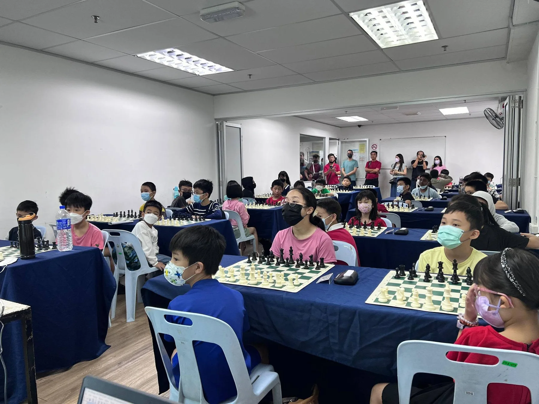 Children seated at prepared chess boards during an organized ITPA chess event