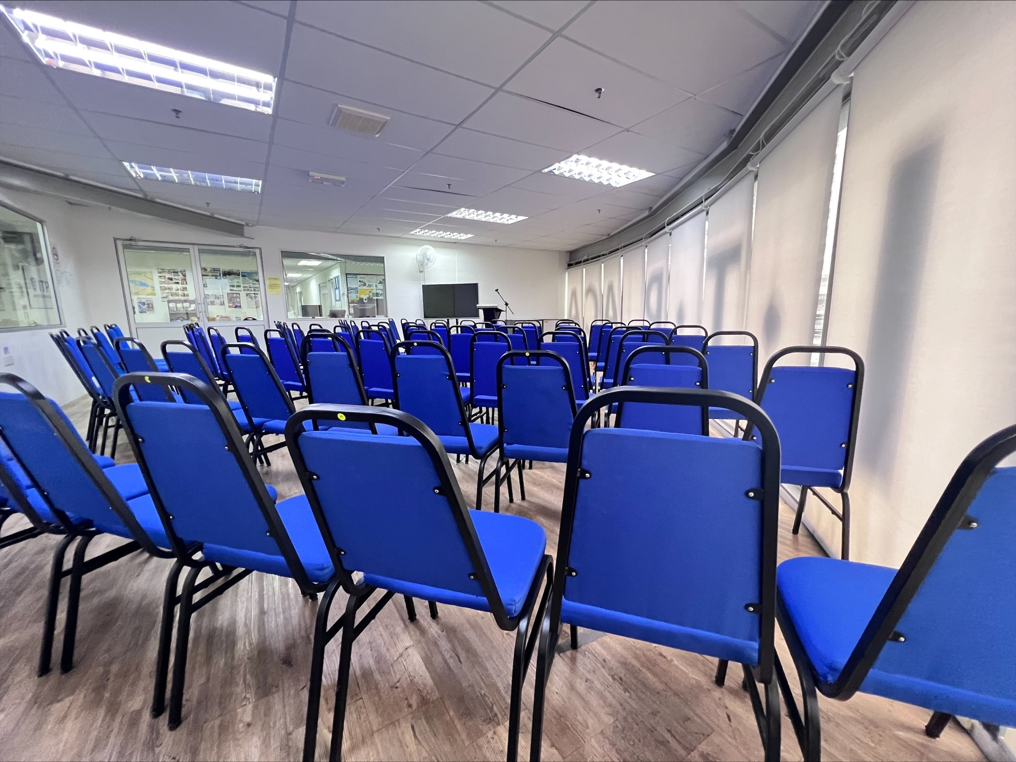 Rows of blue chairs facing the presentation screen and lectern at ITPA Penang