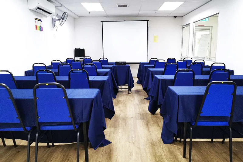 ITPA training room arranged in classroom style with blue chairs, tables and a projector screen